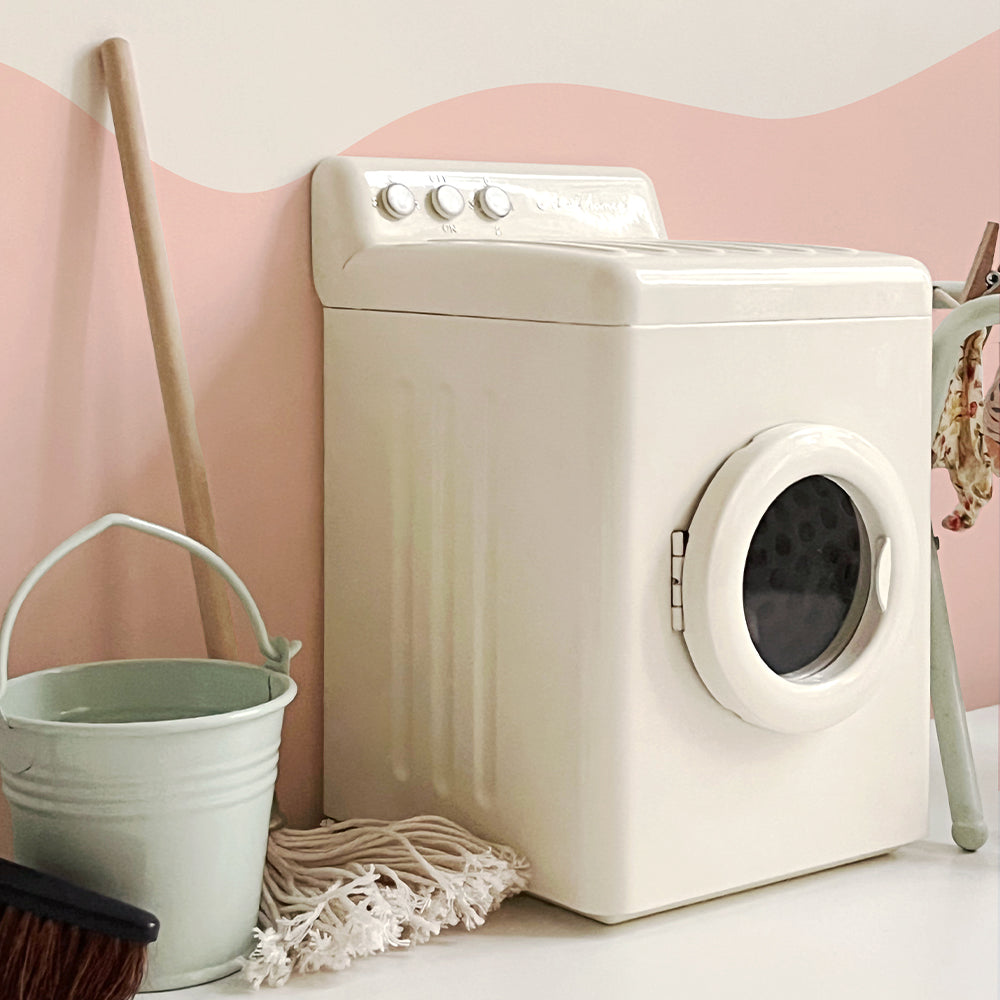 Angled view of an off-white miniature washing machine with closed door, a mint bucket, mop and drying rack beside it